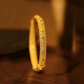 Pulsera tipo brazalete con piedras preciosas verdes doradas y patrón floral de estilo étnico.
